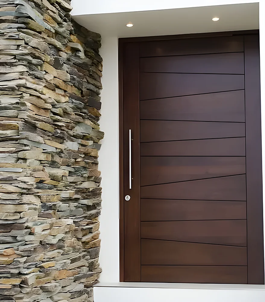 Puerta blindada modelo La Paz, de madera oscura con cantería en bajo relieve y tirador largo