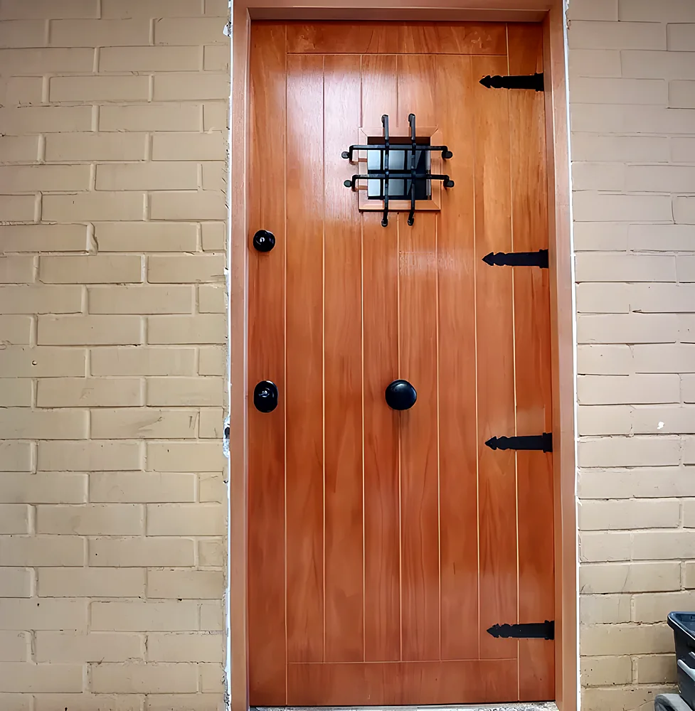 Puerta blindada modelo Londres, de madera con herrajes forjados y mirilla con reja